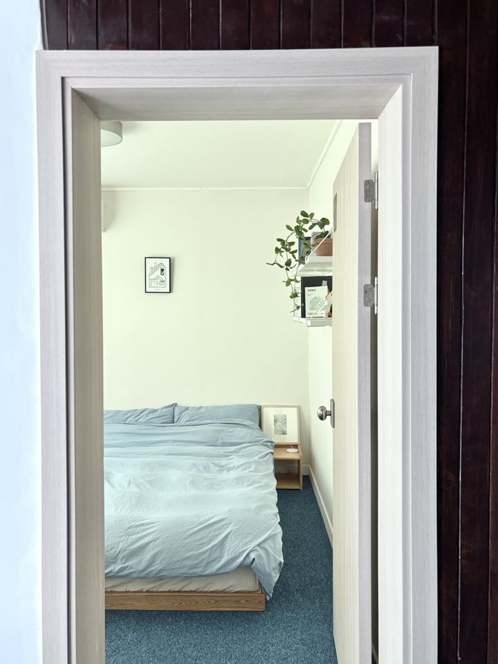문틀 너머로 보이는 침실 — 하늘색 침구